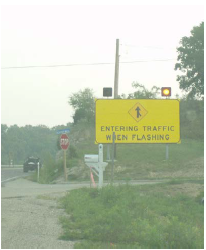 Dynamic warning sign with flashers that activate to warn approaching through traffic that there is a vehicle on a cross road stop approach that may enter the intersection.