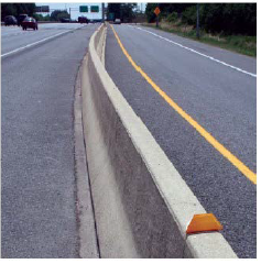 A concrete barrier separating traffic traveling in opposite directions on a multi-lane rural highway.