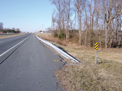 Photo. This photo shows a turned down end treatment where the guardrail is turned down and burried in the ground.
