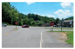Photo of a stop-controlled rural intersection where the opposite lanes on the stop approach are separated by a splitter island.