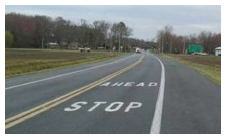 Image shows a roadway with a 'Stop Ahead' pavement marking