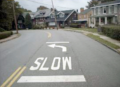Photograph of curve warning pavement markings ('SLOW' and an arrow)