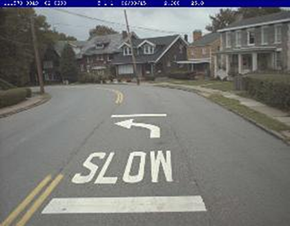 Photograph of curve warning pavement markings ('SLOW' and an arrow)