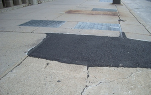A wedge has been placed to mitigate the hazard caused by a raised sidewalk slab.