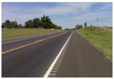 Photo of a rural two-lane roadway featuring center line rumble strips and rumble stripes on the white edge markings.