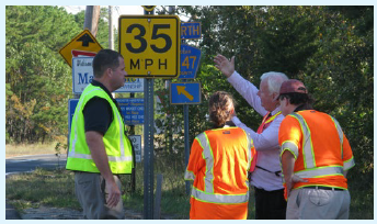 A road safety audit team conducting a field review of a cluster of roadside signs.