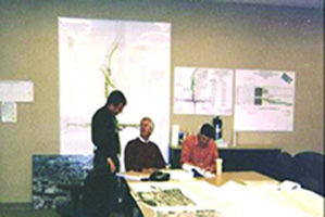 A 3-member RSA team reviews design drawings and other documentation in a workshop setting.