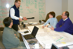Photo showing four people at a table discussing findings.