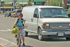 Photo showing a young girl on a bicycle stopped at and intersection.