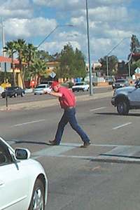 Photo showing a pedestrian crossing within a painted crosswalk in front of traffic.