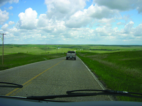 Photo 4 is a two-lane rural road surrounded by undeveloped land. In each picture there are only one or two cars on the roadways.