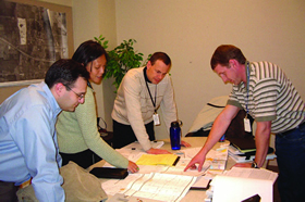 RSA analysis session. Members from an RSA audit team stand over a table looking over information gathered for a project location.
