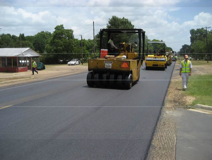 photo of fresh asphalt with rubber tire roller behind two steel drum rollers that are following the paver.
