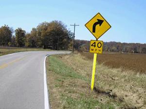 Photo of a 40 miles per hour turn sign with a four inch edge-line marking along the road.