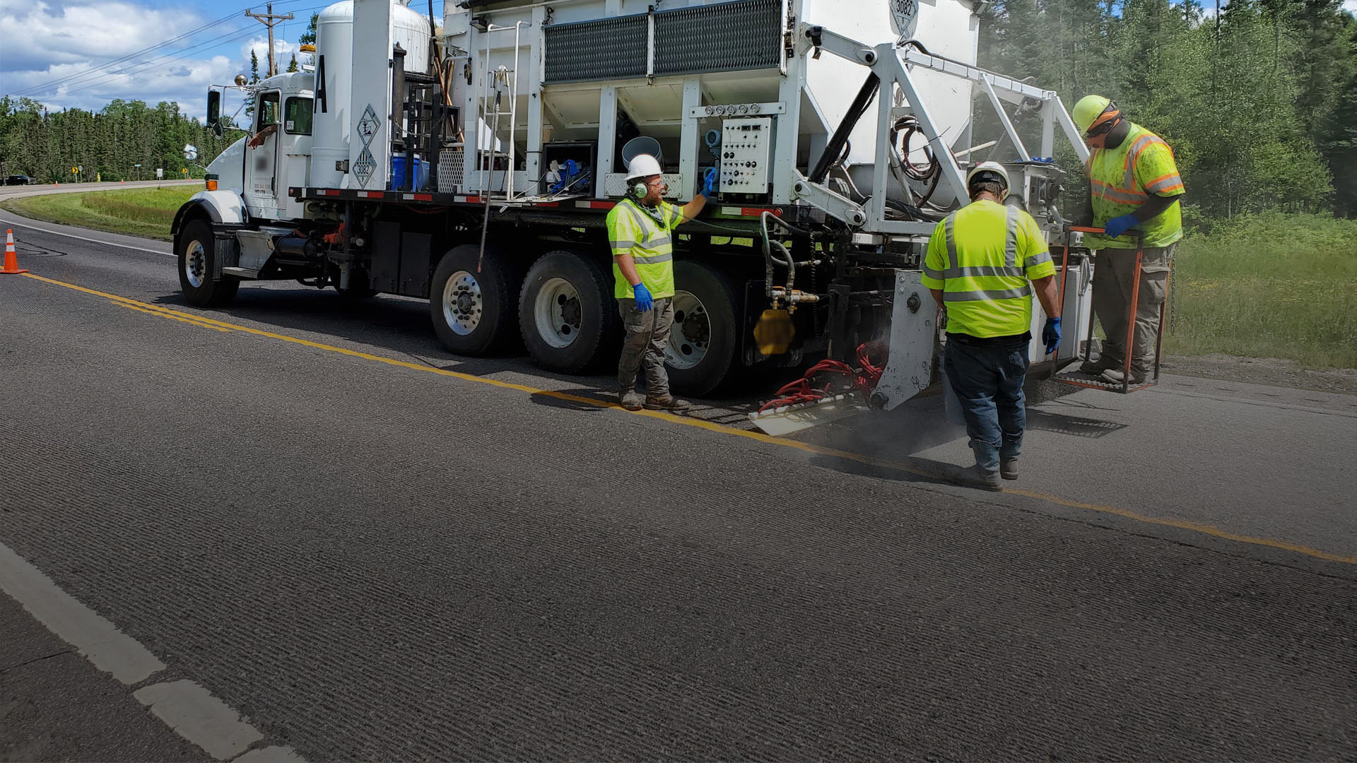 Image of road crew following a truck administering HFST material.