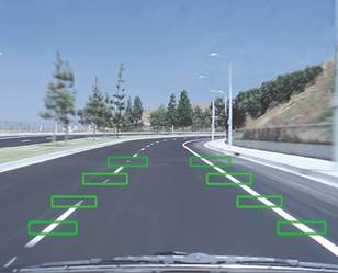 Figure 7. Photo with illustration. Lane departure warning system (virtual rumble strip). This photo shows a roadway right before a curve, with graphics overlaid on the photo. The lane departure system shows a series of green boxes at the right and left edges of the travel lane, serving as virtual rumble strips, to detect lane departures.