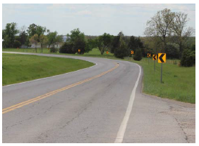 Series of post-mounted chevrons on the side of a curving road.