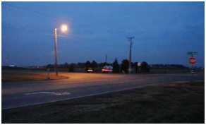 A pole-mounted light illuminates an intersection at night.