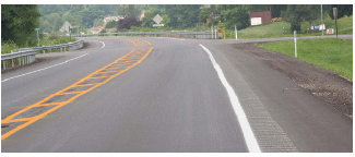 Roadway with rumble strips on the outside shoulders and in a painted yellow median island