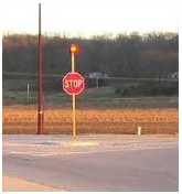 A stop sign with a flashing beacon mounted above it.