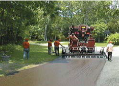 Workers applying a surface friction treatment on a rural roadway