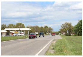 Rural two-lane roadway with a broad clear space to both the left and right of the roadway.