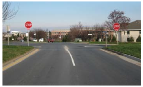 A minor road approach to an intersection contains two stop signs (one on each shoulder) and a highly visible stop bar.