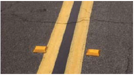 Raised pavement markers to the right and left of a double yellow center line.