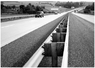 A guardrail down the center of a median-separated four-lane highway.