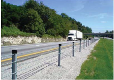A cable barrier separates a roadway from a steep incline to the right of the shoulder.