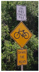 A series of signs mounted on a single post warn bicyclists to ride single file, advise drives that bicyclists may be present, and advise both groups to share the road.