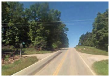 A rural two-lane road with two driveways opposite each other.