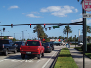 The photo shows a busy signalized intersection with a sidewalk off to the right.