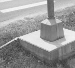 This support system is now a hazard as it constitutes a rigid concrete block more than four inches above the surrounding ground. This can snag the under-carriage of a vehicle causing it to stop abruptly or go out of control.