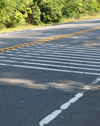 Photo.  A photo of roadway (or transverse) rumble strips which are raised bars or grooves placed across the travel lane that can be either black or white.