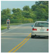 Photo.  A two lane roadway with a bicycle riding on a paved shoulder.
