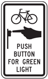 Graphic.  A black and white sign directing pedestrians and bicyclists to use push buttons at signalized intersections.