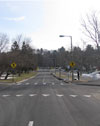 Photo.  A photo depicting pavement markings used at crosswalks as a supplement to a Yield Here to/Stop for Pedestrians sign.  the pavement markings in the photo include a crosswalk along with a yield line.