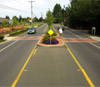 Photo.  A photo of in-roadway warning lights at a crosswalk.  The lights are amber flashing lights embedded in the pavement on both sides of a crosswalk and oriented to face oncoming traffic, these serve as a warning for motorists when a pedestrian is in the crosswalk. The amber LED lights flash in unison and are visible during the daylight, as well as at night.