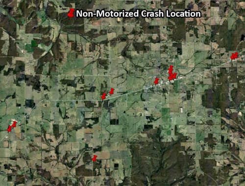 Graphic.  A graphic of a pushpin map.  The pushpin map is an aerial photograph of the region studied.  There are red pushpins indicating the location of non-motorized crashes.