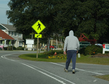 Photo.  A pedestrian walking with the flow of traffic along the shared use shoulder.