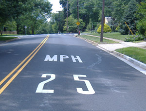 Photo. A pavement marking of '25 MPH' to encourage speed reduction for an impending curve. 