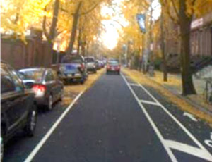 Photo. A street where lane widths were reduced to provide exclusive space for cyclists. Through a reduction in lane width, the road currently has one on-street parking lane, one travel lane, and one bike lane. 