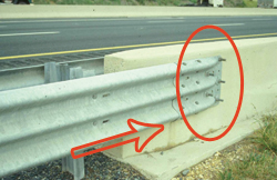 Photo. This photo shows a transition from a guardrail to a bridge parapet. The bolt heads are circled to highlight protrusion.