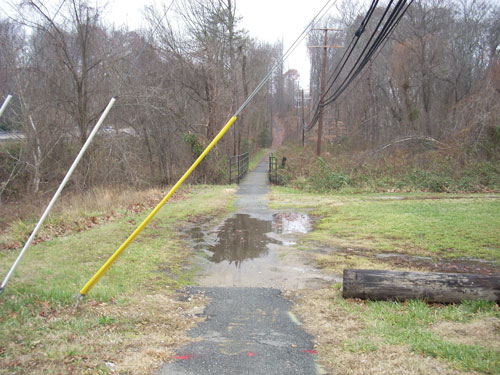 Photo. This photo shows a paved pedestrian, bicycle path that has a significant pool of water in the travel way.