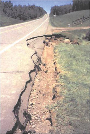Photo. This photo shows the edge of a roadway where the pavement is deteriorated and crumbling.