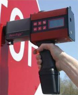 Photo. A retroreflectometer is being used to test a sign.