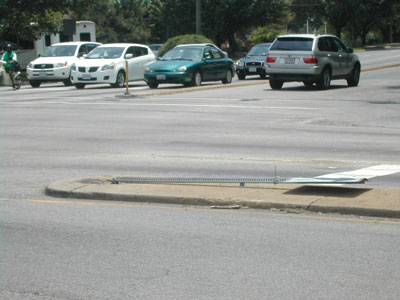 Photos. The first photo depicts a sign that has been knocked down on a median. 