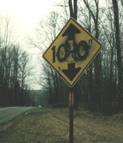 Photo. A sign damaged by overpainting is shown.