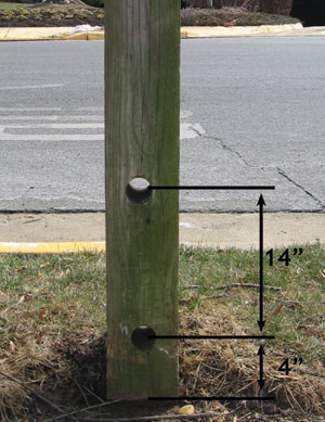 A large wood sign post with two holes drilled in it at 4 and 14 inches above the ground.